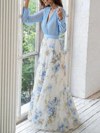 Light blue V-neck maxi dress with long sleeves, fitted waist, and floral print skirt