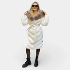 Long white puffer jacket with taupe fur hood, button front, and waist tie belt.
