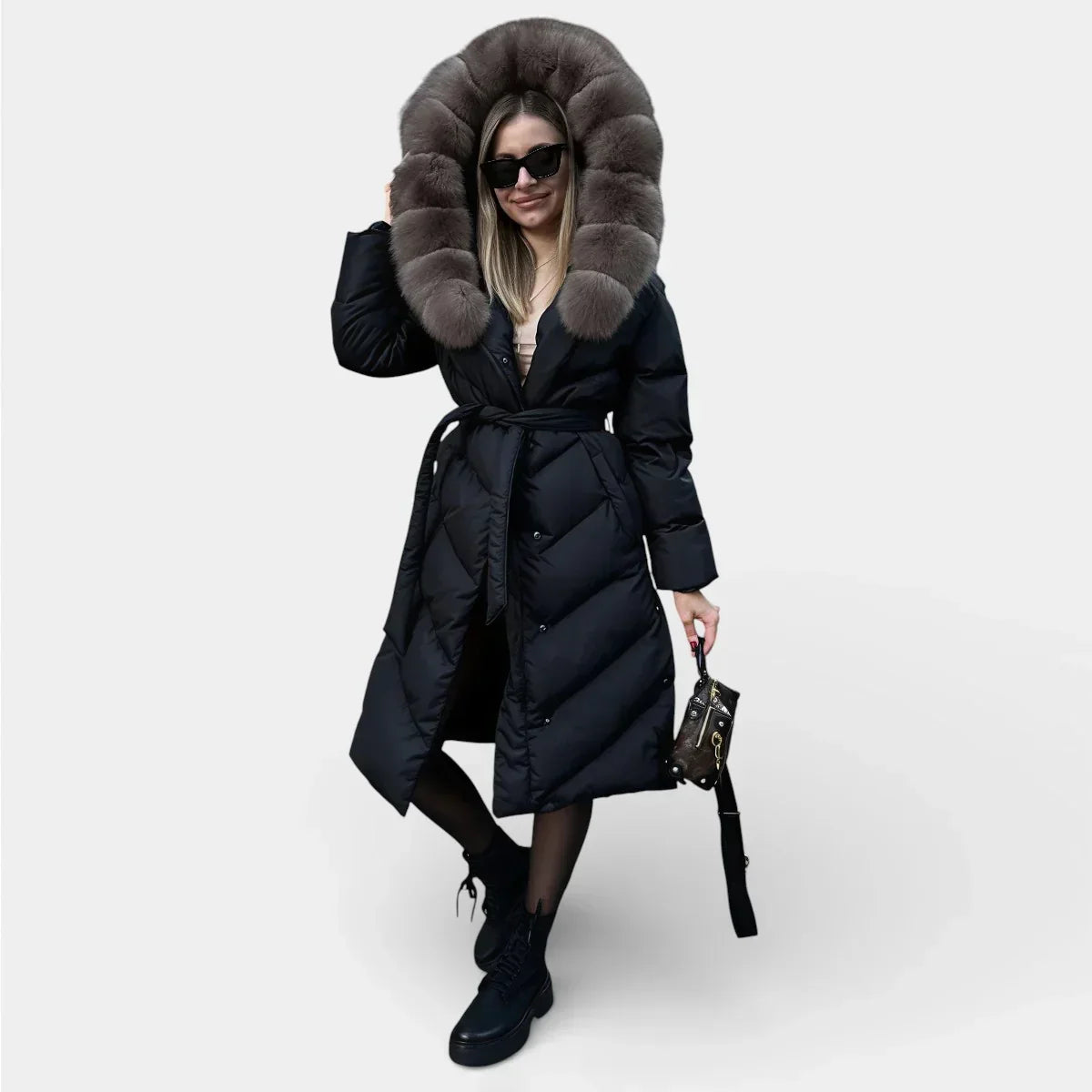 Long black puffer jacket with taupe fur hood, button front, and waist tie belt.