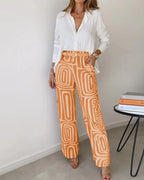 Two-piece set: white button-front blouse with orange patterned wide-leg pants