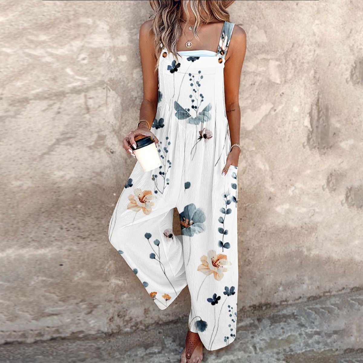 White sleeveless jumpsuit with blue floral and leafy print, wide-leg fit