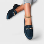 Navy suede loafers with gold buckle strap and decorative chain detail, side angle
