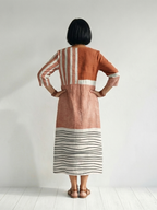 Back view of rust midi dress with V-back, vertical stripes, and striped hem band