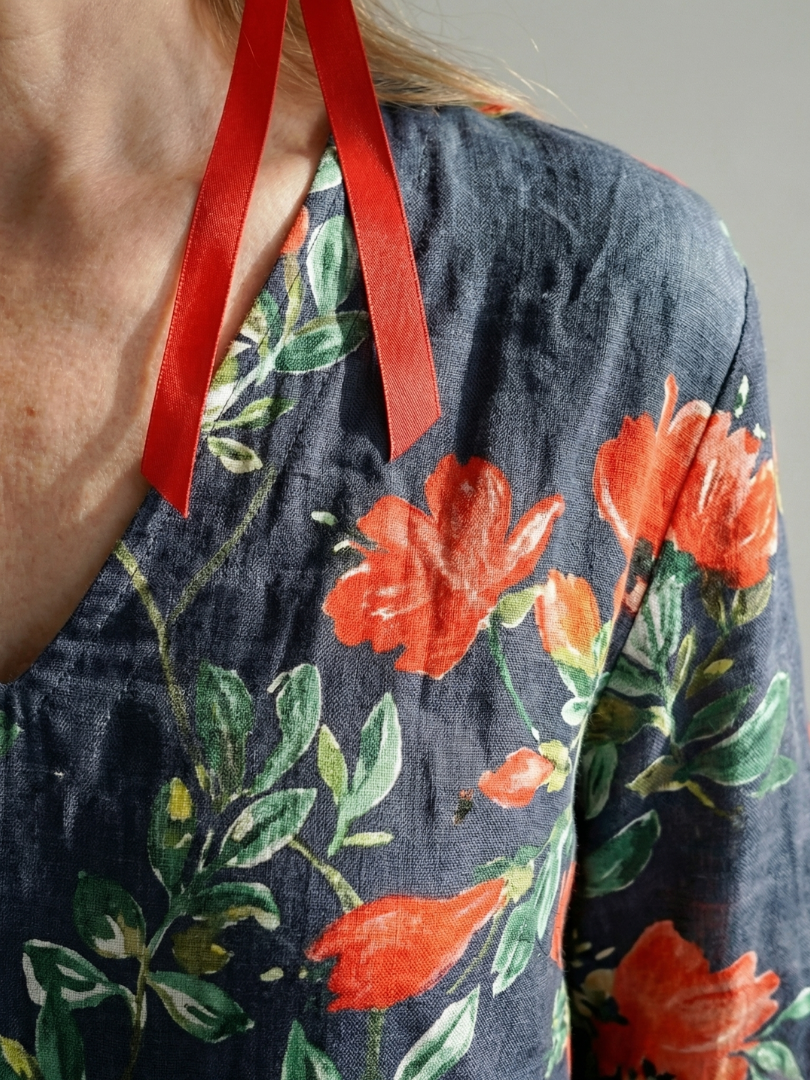 Floral midi dress detail with red ribbon tie and orange flowers on dark fabric