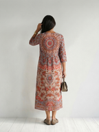 Red patterned midi dress, back view with 3/4 sleeves and round neckline.