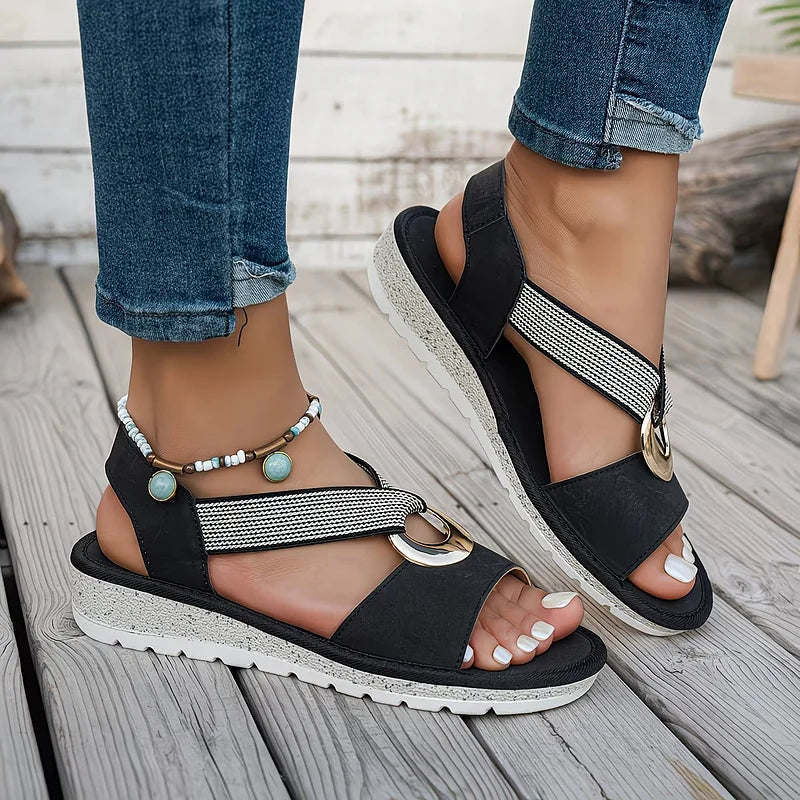 Black flat sandals with mesh strap and round metal buckle on cushioned sole