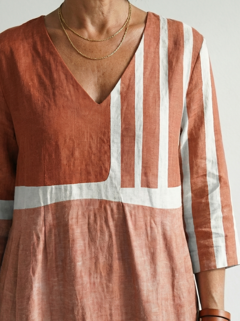 Rust midi dress close-up: V-neck bodice with vertical stripes and pale horizontal band