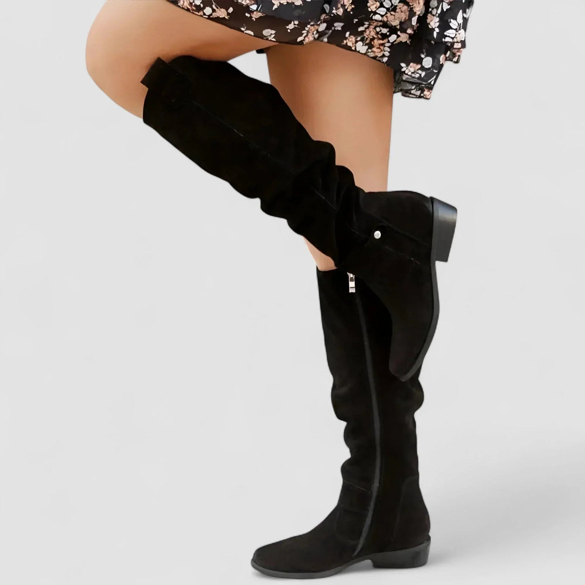 Black knee-high western boots with side strap accents and low stacked heel.