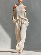 Cream knit cold-shoulder turtleneck top with long sleeves and tie-waist wide-leg pants.