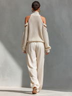Back of cream knit cold-shoulder turtleneck top with tie-waist wide-leg pants.