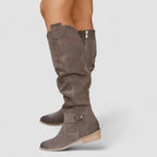 Brown knee-high western boots with side buckle strap and low stacked heel.
