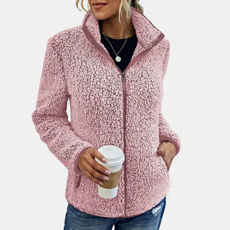 Pink teddy jacket with full-zip front and stand collar, worn with jeans.