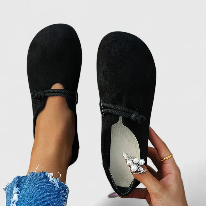 Black suede slip-on loafers with tie strap and embellished side charm
