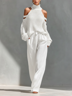 Cream knit cold-shoulder turtleneck top with off-shoulder cutouts and tie-waist wide-leg pants.