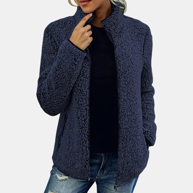 Navy teddy jacket with full-zip front and stand collar, worn over dark top.