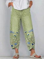 Green casual trousers with blue-and-white floral embroidery panels on the sides