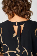 Women's black dress close-up: gold swirl print and keyhole back with tie strap