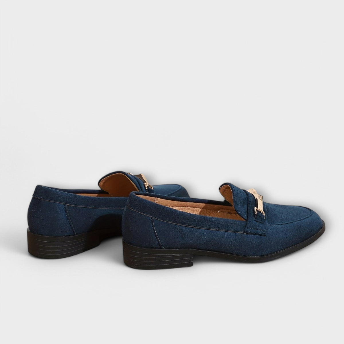 Navy suede loafers with gold buckle strap detail and low block heel, rear angle