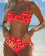 Red abstract print bikini with thin straps, knot bandeau top, and ruched tied bottoms