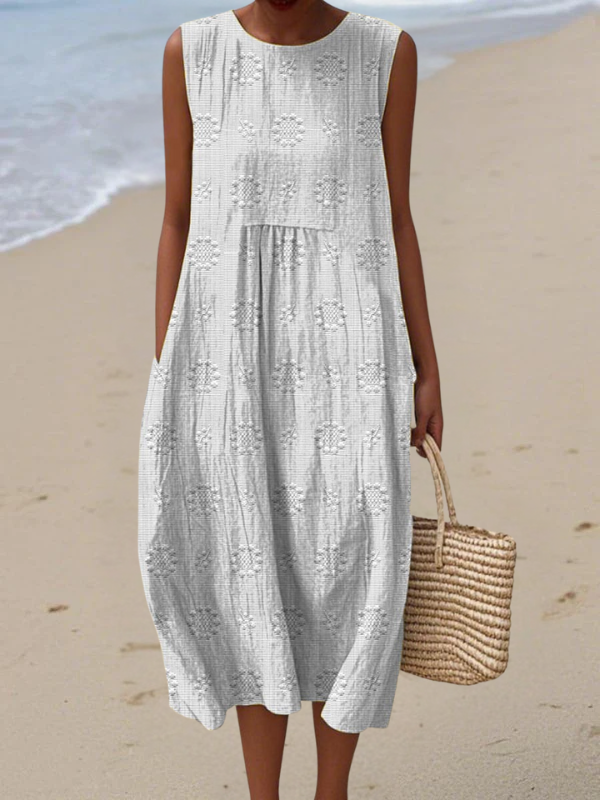 White embroidered midi dress with sleeveless tiered skirt and round neckline.