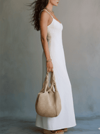 White sleeveless strappy maxi dress with side slit, tan woven tote bag