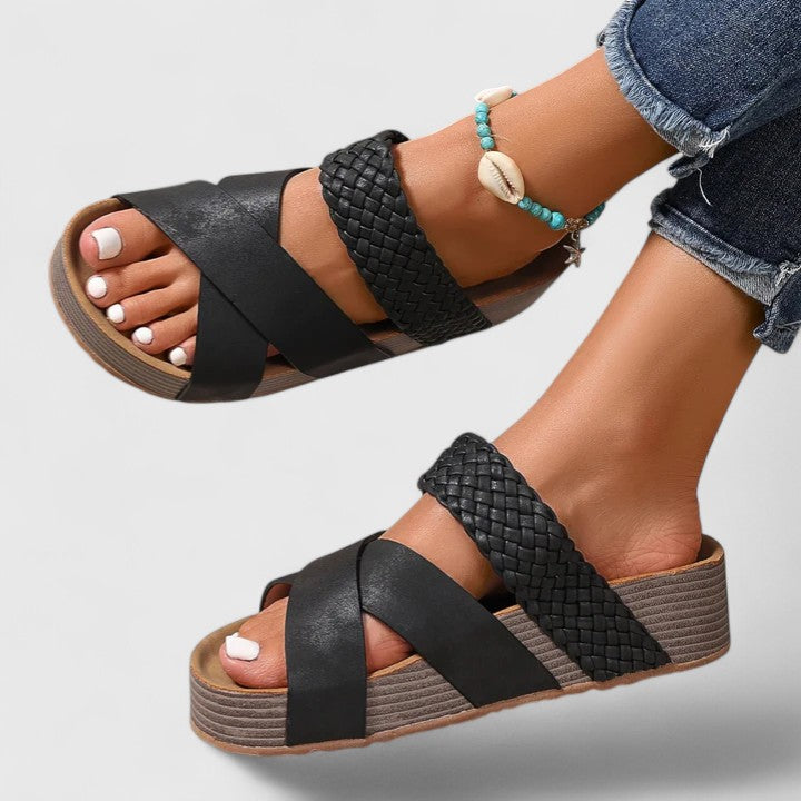 Black orthopedic sandals with woven cross straps and cushioned platform wedge sole