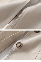 Beige trench coat fabric close-up with stitched seams and round metal button