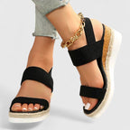 Black orthopedic sandals with wide straps, tan espadrille sole, and gold chain ankle strap
