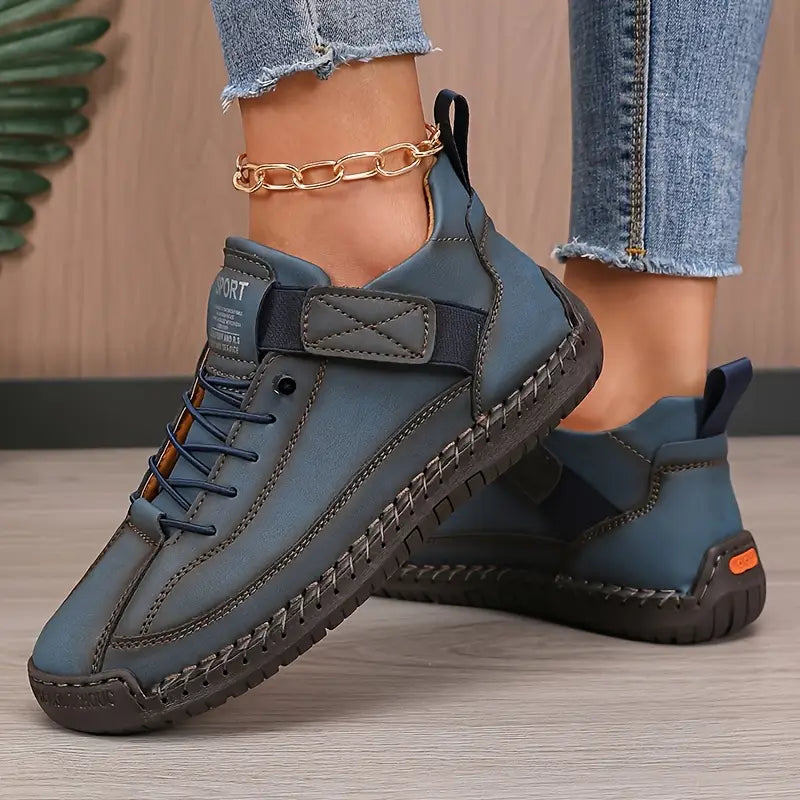 Blue comfort support sneaker with lace-up, ankle chain, and orange pull-tab accent