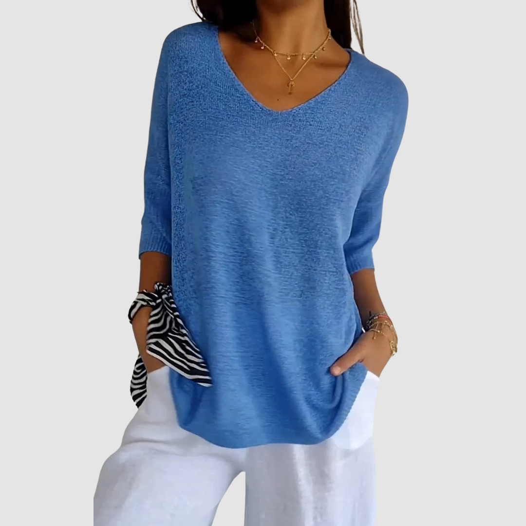 Blue knit v-neck top with three-quarter sleeves and a loose draped silhouette.