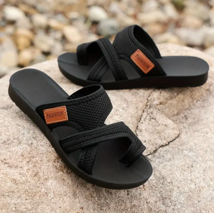 Black orthopedic slide sandals with crisscross straps and tan 'FASHION' patch