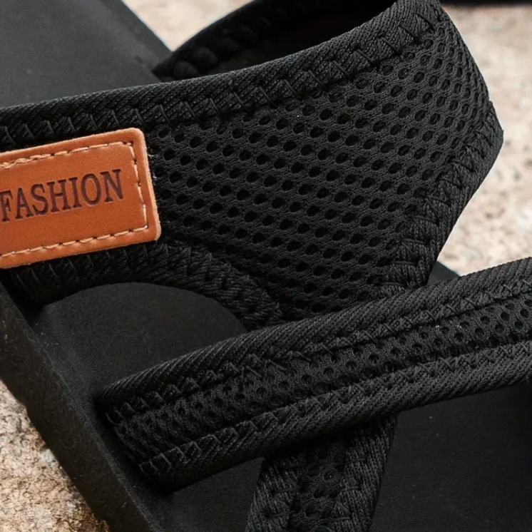 Black orthopedic sandals close-up: textured knit straps with tan 'FASHION' label
