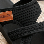 Black orthopedic sandals close-up: textured knit straps with tan 'FASHION' label