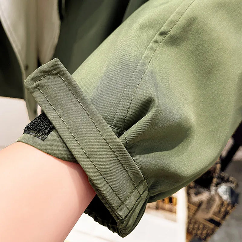 Olive green windbreaker jacket sleeve cuff with adjustable tab and seam detail