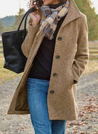 Beige long coat with notch lapels, dark button front, and side pockets.