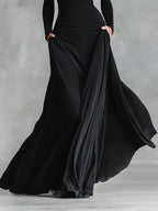 Black pleated maxi skirt with ruched waist detail and flowing draped panels