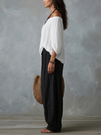 White off-shoulder top with black loose lantern pants, side view