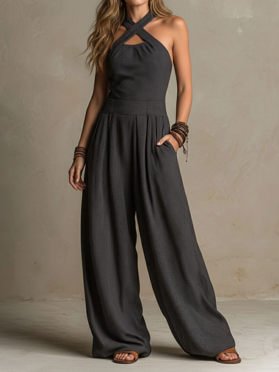 Charcoal halter jumpsuit with crisscross neck, pinstripe texture, and flowing wide legs