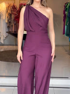 Purple one-shoulder jumpsuit with diagonal sash drape and relaxed wide-leg fit