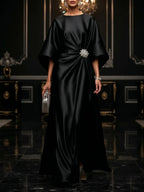 Black satin maxi dress with square neckline, draped waist and flower brooch detail
