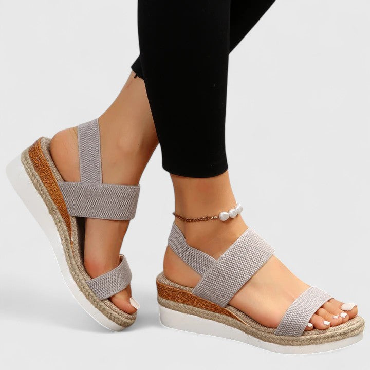 Light gray orthopedic sandals with wide straps, tan espadrille sole, and pearl ankle bracelet