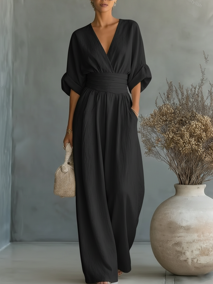 Black V-neck high-waist jumpsuit with cinched waist and wide-leg flow, dolman sleeves