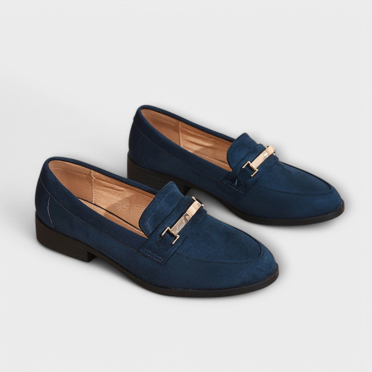 Navy suede penny loafers with gold buckle strap and low block heel, pair front