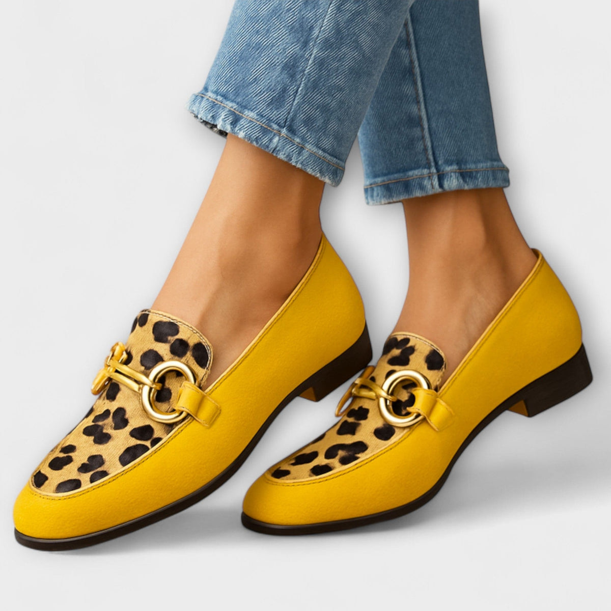 Yellow animal print slip-on slippers with rounded toe and gold buckle detail