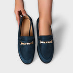 Navy suede loafers with gold buckle strap detail, showing inner lining and toe shape