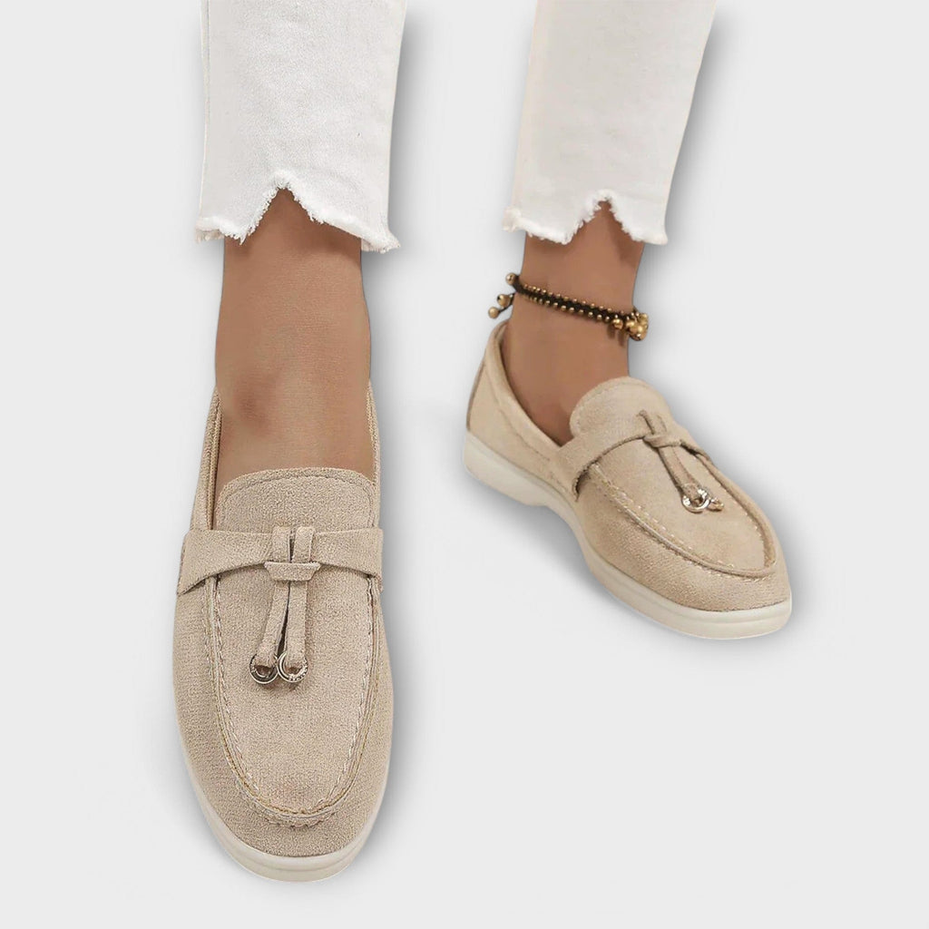 Beige women's suede loafers, side view, with tie bow strap and low sole