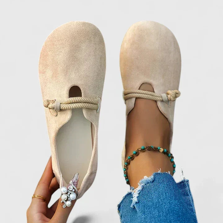 Beige suede slip-on loafers with braided tie strap and decorative bow detail