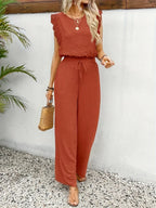 Rust red sleeveless two-piece outfit with tied waist and wide-leg trousers