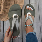 Green flat sandals with textured strap and round metal buckle