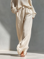 Cream knit cold-shoulder top with tie-waist wide-leg pants, relaxed gathered look.